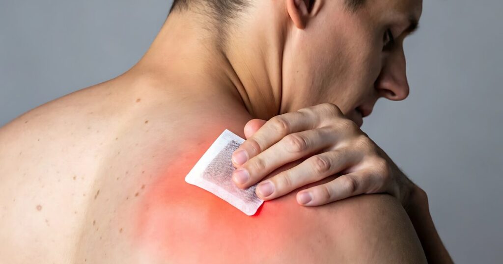 man putting a hot compress pad on his shoulders