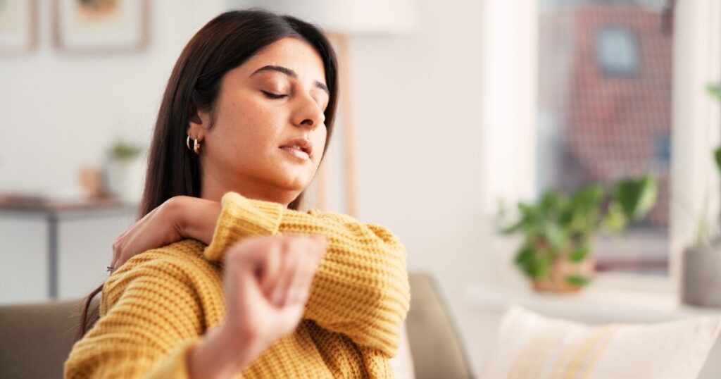 woman that looks tired and holding her shoulders due to pain