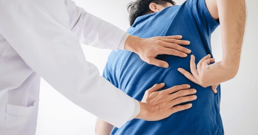 man pointing out back pain to doctor