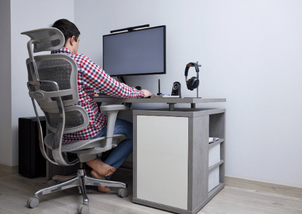 A person sitting at a desk using a computer in a home office.