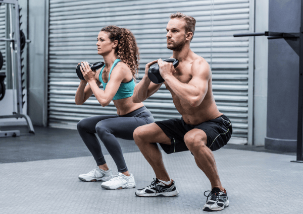 man and woman working out using kettle bells