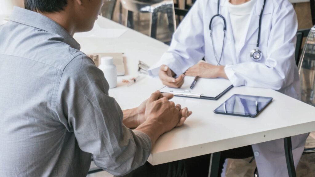 A doctor sitting at a table talking with a patient during a checkup