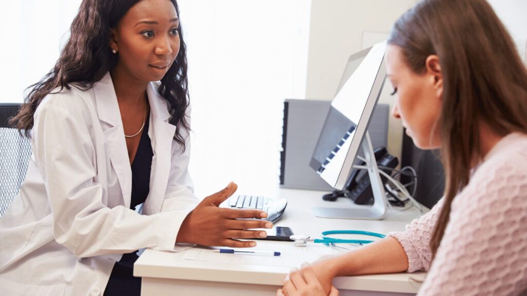 A doctor speaking with a person in a white coat during a medical consultation